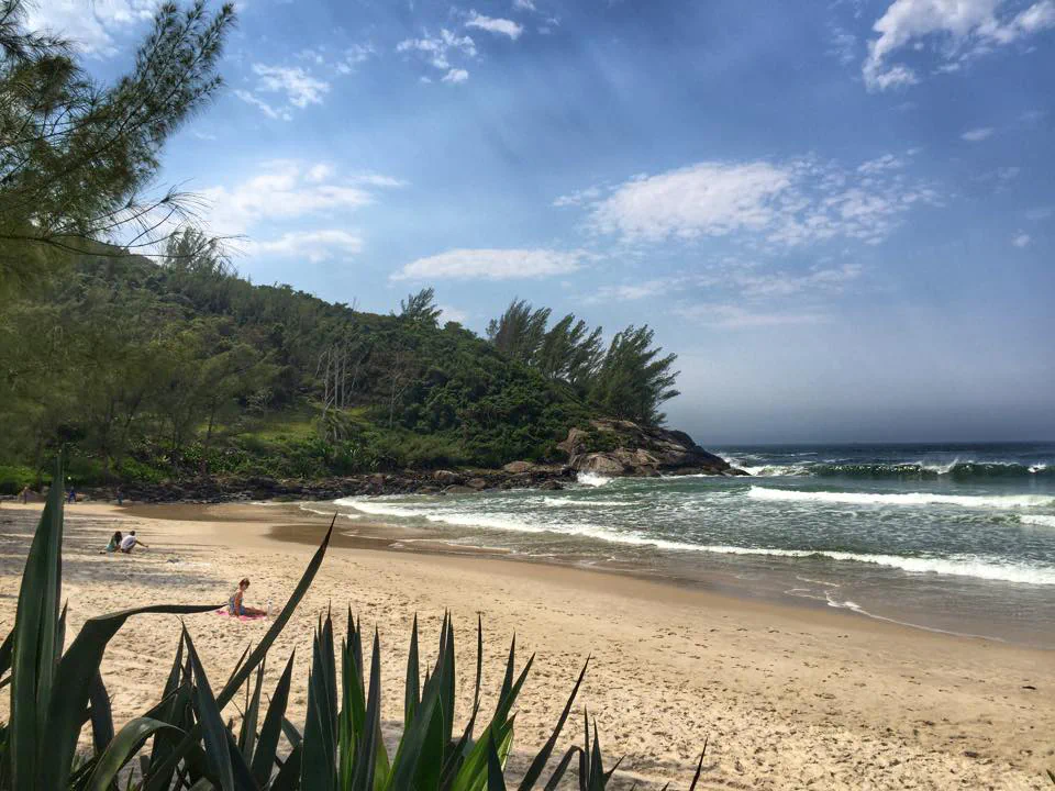 Praia da Ferrugem com mar azul e costão em Garopaba
